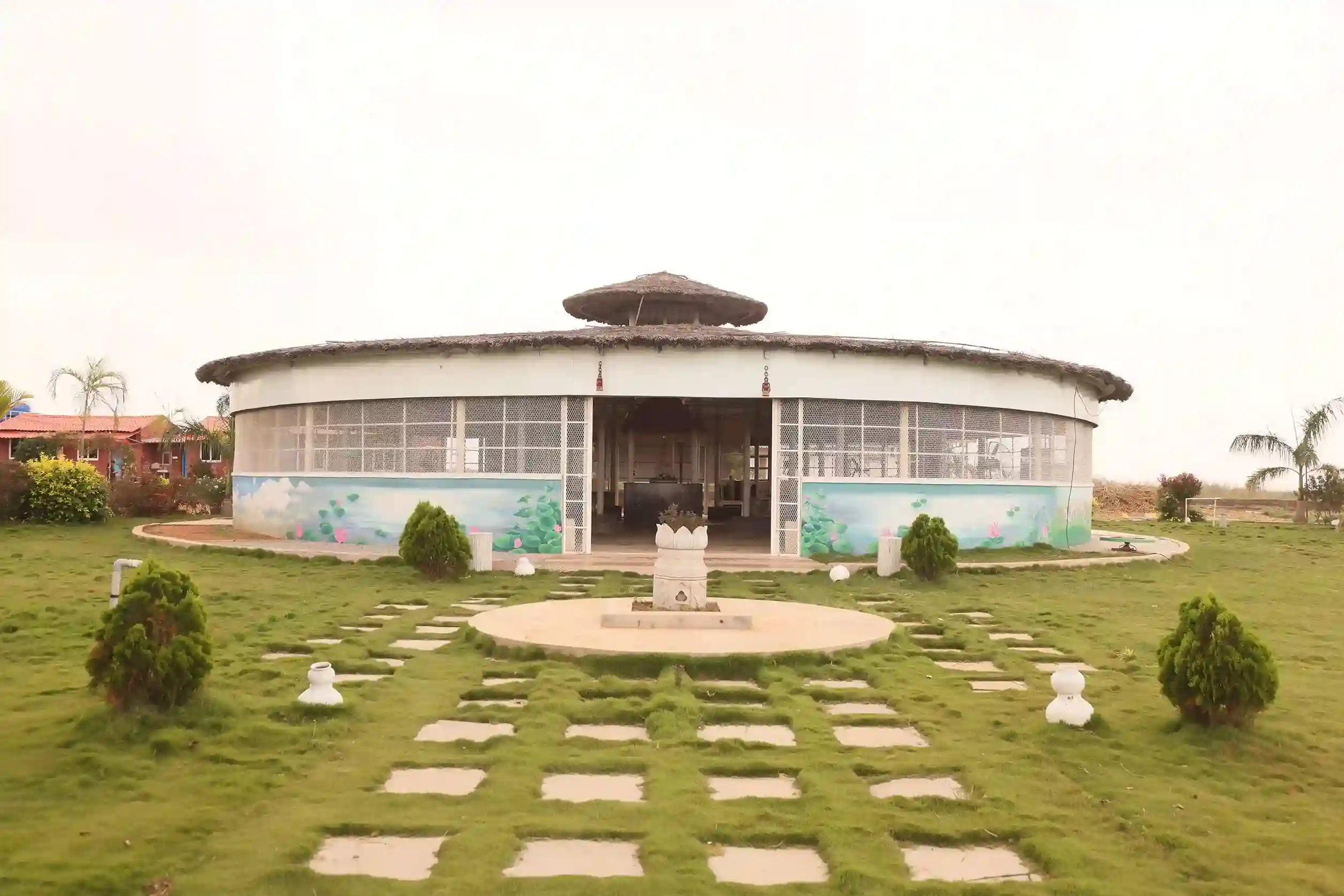 A circular community building at Farm Natura with a lush green lawn.